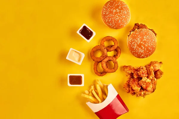 Вид зверху гамбургер, картопля фрі та смажена курка на жовтому тлі. Копіювати простір для вашого тексту . — стокове фото
