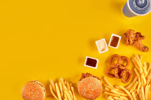 Piatto fast food vista dall'alto. Patatine fritte, hamburger, maionese e salse al ketchup su fondo giallo . — Foto Stock