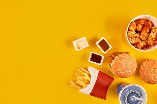 Фаст-фуд блюдо вид зверху. Картопля фрі, гамбургер, майонез, кетчуп і соус на жовтому фоні. — стокове фото