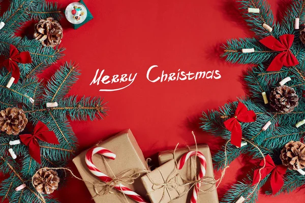 Köknar dalı ve hediye kutu kırmızı arka plan. Yazıt - Merry Christmas