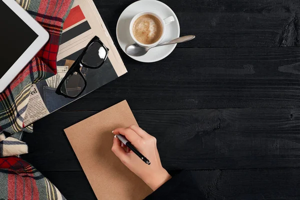 Жіночі руки тримають ручку над столом з чашкою кави, ноутбука та планшета — стокове фото