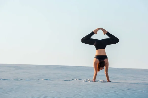 Junge Frau übt Inversion balancierende Yoga-Haltung Handstand auf Sand. — Stockfoto