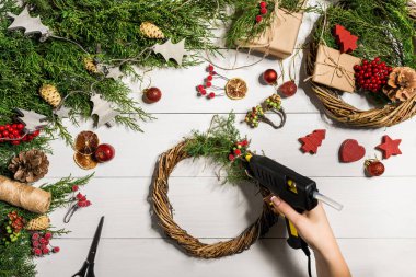 Noel el yapımı DIY arka plan. Yapımı craft xmas çelenk ve süsler. Beyaz ahşap masa eller ile Üstten Görünüm.