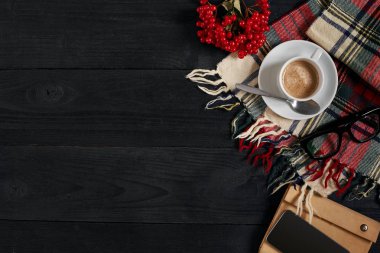 Siyah ahşap zemin üzerine defter ve latte kahve fincan ile akıllı telefon görünümünün üst.