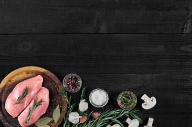 Otlar ve baharatlar ile ahşap kesme tahtası üzerinde çiğ tavuk göğsü fileto. kopya alanı ile Üstten Görünüm