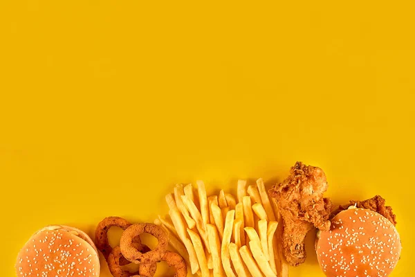 Fast food dish on yellow background. Fast food set fried chicken, meat burger and french fries. Take away fast food.