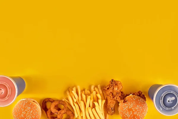 Fast food dish on yellow background. Fast food set fried chicken, meat burger and french fries. Take away fast food.