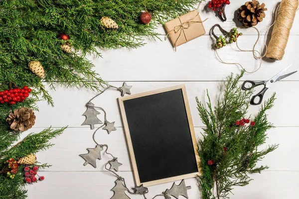 Wacholderzweige mit Weihnachtsdekor. Weihnachten, Neujahr Hintergrund. Nadelzweige aus Wacholder und schwarze Schreibtafel. von oben, flache Bauweise. — Stockfoto