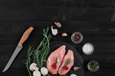 Tavuk göğsü otlar, baharatlar ve rustik ahşap arka plan üzerinde bıçak ile kesme tahtası.
