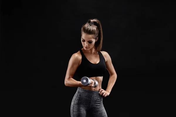 Mujer atlética con mancuernas haciendo ejercicio deportivo, sobre fondo negro —  Fotos de Stock