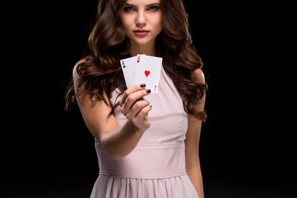 Sexy brunette woman holding aces winning hand on a black background