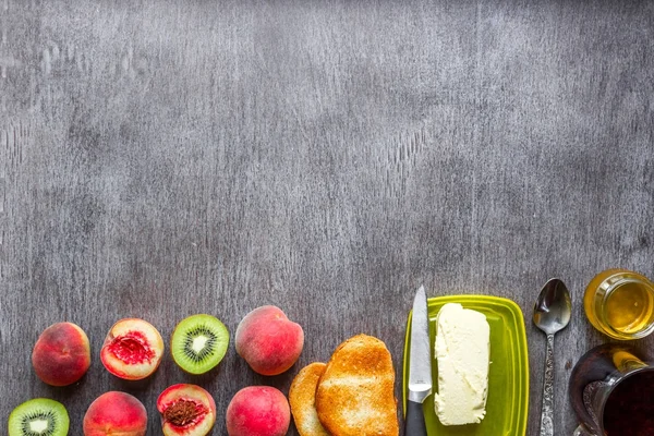 Concepto de desayuno saludable. Tostadas con mantequilla, miel, frutas y té sobre fondo de madera oscura — Foto de Stock