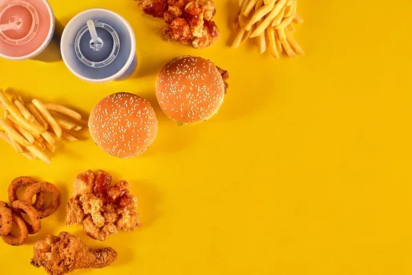 Fast food dish on yellow background. Fast food set fried chicken, meat burger and french fries. Take away fast food.