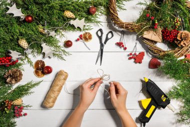 Noel el yapımı DIY arka plan. Yapımı craft xmas çelenk ve süsler. Beyaz ahşap masa eller ile Üstten Görünüm.