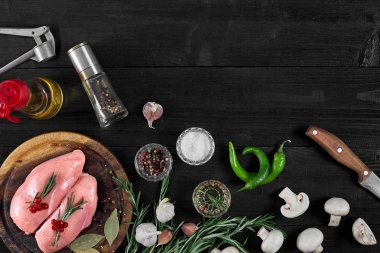 Çiğ tavuk göğsü fileto otlar, baharatlar, mantar ve biber ahşap kesme tahtası üzerinde. Kopya alanı ile Üstten Görünüm