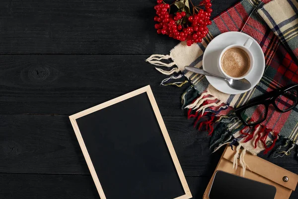 Tazza da caffè, sciarpa in gabbia, taccuino e telefono sul tavolo di legno. Vista dall'alto con lavagna per il testo — Foto Stock