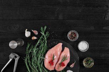 Tavuk göğsü kesme tahtası otlar, baharatlar ve sarımsak ile basın rustik ahşap arka plan üzerinde.