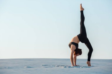 Genç kadın Yoga poz amut kum üzerinde Dengeleme inversiyon pratik.