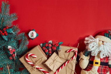 Köknar dalı, hediye kutusu ve oyuncak Santa kırmızı zemin üzerine