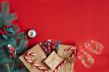 Köknar dalı, hediye kutusu ve iki bardak şampanya kırmızı zemin üzerine