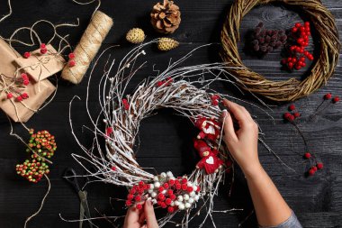 Eller üstten görünüm olun Noel çelenk. Yemeği hediyeler ve verilirse, şube ve ahşap masa üstünde alet çeki düzen vermek.