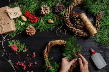 Eller üstten görünüm olun Noel çelenk. Yemeği hediyeler ve verilirse, şube ve ahşap masa üstünde alet çeki düzen vermek.