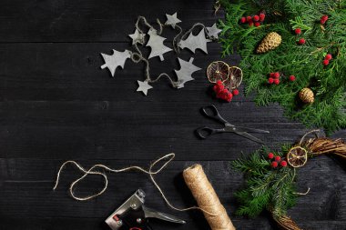 Kendi ellerinle bir Noel çelenk olun. Ladin şube, Noel çelenk ve hediyeler siyah ahşap zemin