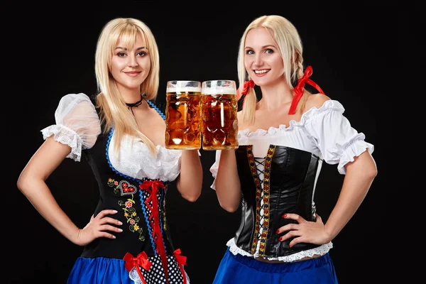 Genç ve güzel Bavyera kızla iki bira bardağı siyah arka plan üzerine — Stok fotoğraf