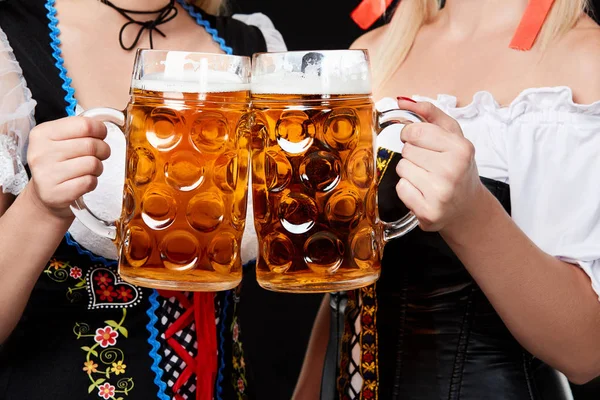 Unga och vackra bayerska flickor med två öl muggar på svart bakgrund — Stockfoto