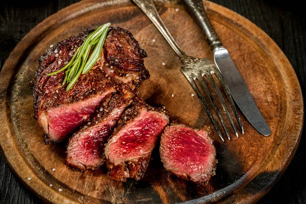 Griller un steak de bœuf juteux avec du sel, du poivre et du romarin . — Photo