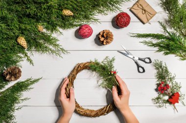 Noel el yapımı DIY arka plan. Yapımı craft xmas çelenk ve süsler. Beyaz ahşap masa eller ile Üstten Görünüm.