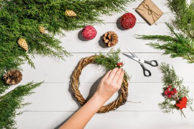Noel el yapımı DIY arka plan. Yapımı craft xmas çelenk ve süsler. Beyaz ahşap masa eller ile Üstten Görünüm.