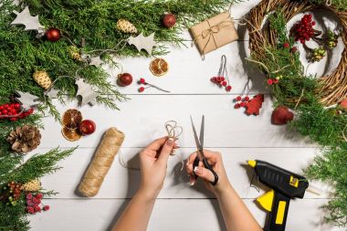 Noel el yapımı DIY arka plan. Yapımı craft xmas çelenk ve süsler. Beyaz ahşap masa eller ile Üstten Görünüm.