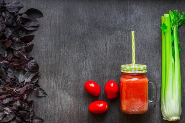 Kereviz ve fesleğen ile baharatlı domates içki. Domates iç ahşap bir masa üzerinde taze sebze çevrili kavanoz içinde