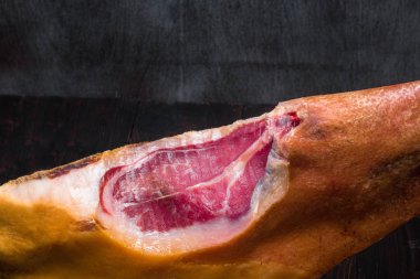 Bir tablo üzerinde yalın bir bıçakla bir ahşap stand Akdeniz geleneksel jamon parçası. Karanlık görüntü