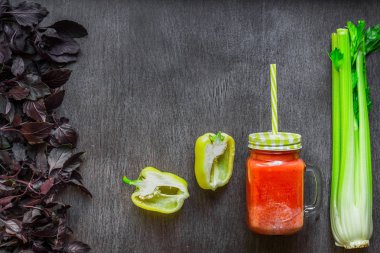 Kereviz ve biber ile baharatlı domates içki. Domates iç ahşap bir masa üzerinde taze sebze çevrili kavanoz içinde