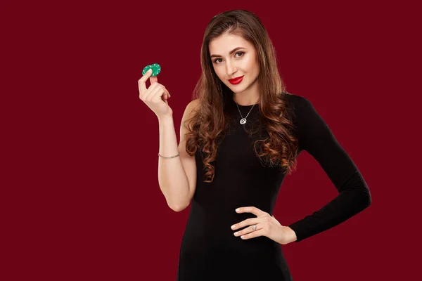 Docela dlouhý vlasy žena v černých šatech, držící čipy pro hazardní hry — Stock fotografie
