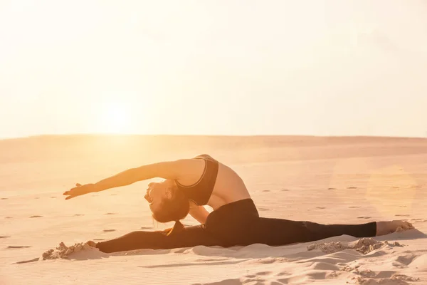 Fitness Yoga Frau dehnt sich auf Sand. fitte Sportlerin in Yoga-Pose. — Stockfoto