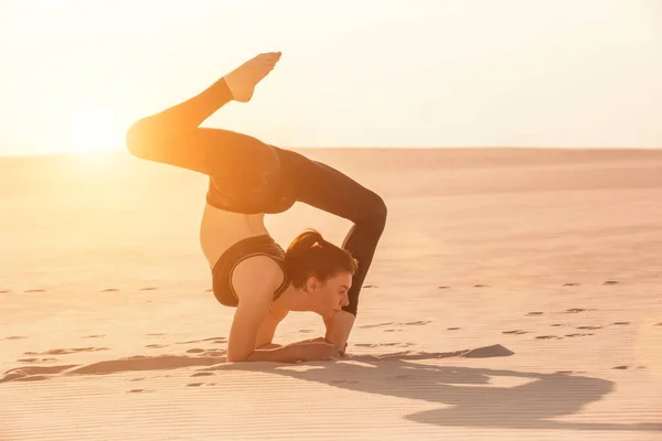 Fitness yoga woman stretching on sand. Fit female athlete doing yoga pose.