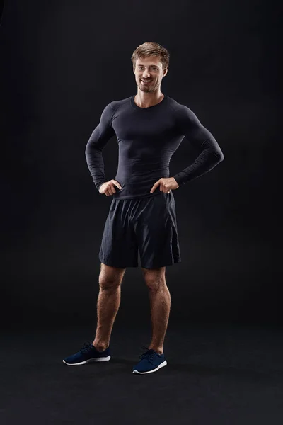 Male model in active sportswear against black background with copy space