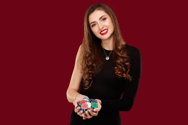 Casino, gioco d'azzardo, poker, persone e concetto di intrattenimento - giocatore di poker donna in abito nero con patatine fritte in mano su sfondo rosso . — Foto Stock
