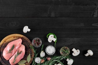 Çiğ tavuk göğsü fileto otlar, baharatlar, mantar ve biber ahşap kesme tahtası üzerinde. Kopya alanı ile Üstten Görünüm