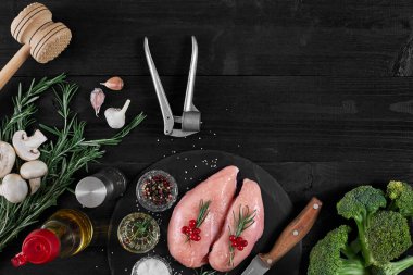 Tavuk göğsü rustik ahşap arka plan üzerinde farklı sebze ve otlar ile kesme tahtası.