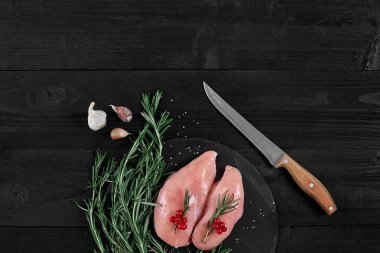 Tavuk göğsü otlar, baharatlar ve rustik ahşap arka plan üzerinde bıçak ile kesme tahtası.