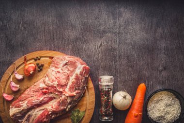 Çiğ domuz eti koyu ahşap yüzey ve yemek pişirmek için malzemeler. Gıda arka plan kopya alanı ile. Tonda