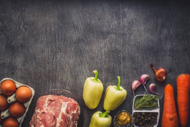 Çiğ domuz eti koyu ahşap yüzey ve yemek pişirmek için malzemeler. Gıda arka plan kopya alanı ile.