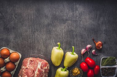 Çiğ domuz eti koyu ahşap yüzey ve yemek pişirmek için malzemeler. Gıda arka plan kopya alanı ile.