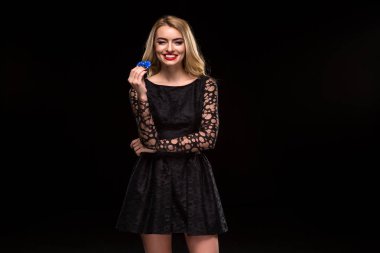 Elinde siyah bir arka plan üzerinde izole casino ile siyah elbiseli güzel sarışın fişleri