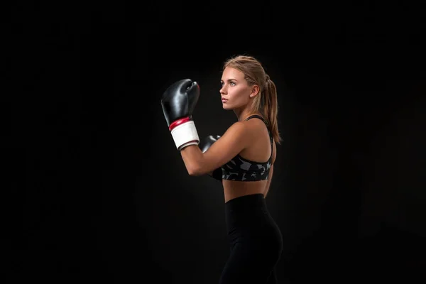 Linda atleta feminina em luvas de boxe, no estúdio em um fundo preto . — Fotografia de Stock