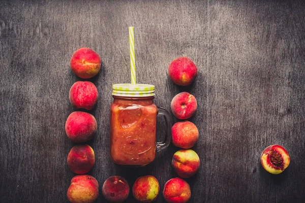 Cam şişe ve ahşap masa üzerinde uçan kuştan şeftali meyve yüzlü. Sağlıklı bir yaşam tarzı. Tonda